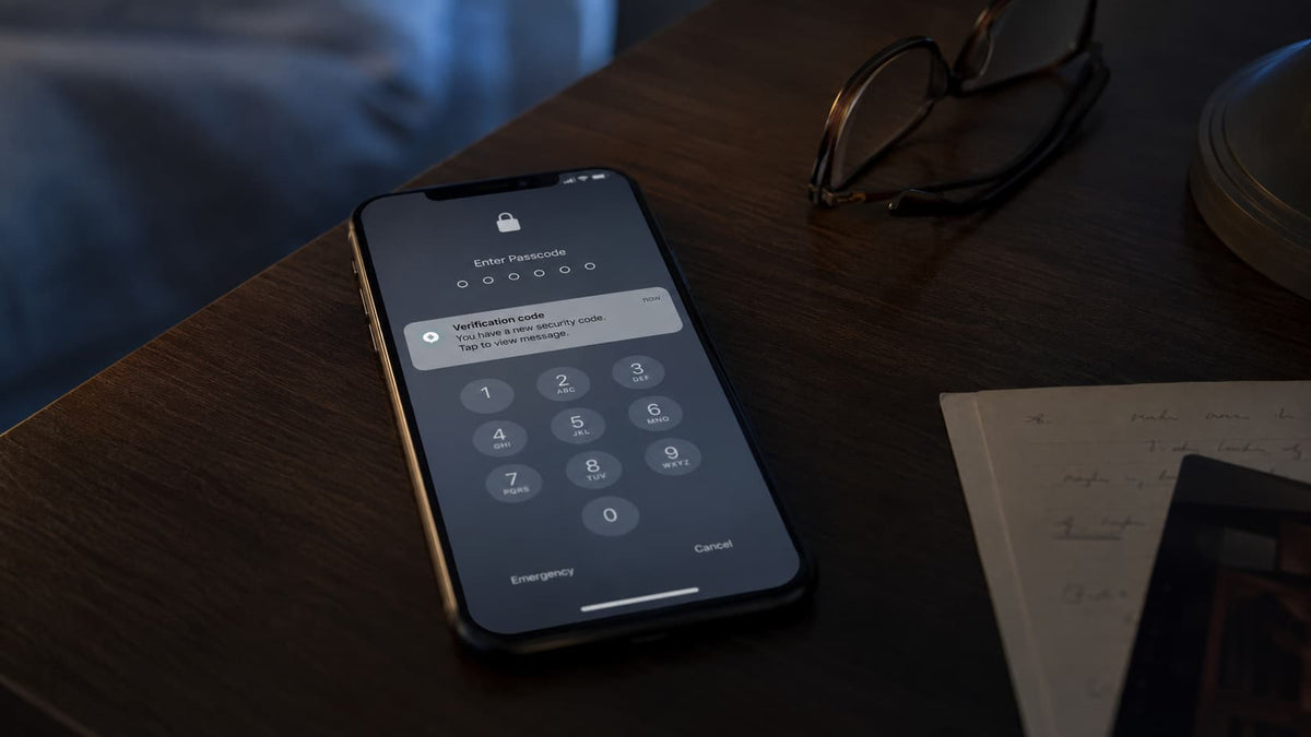A locked smartphone on a table showing a passcode screen and an unread verification-code message